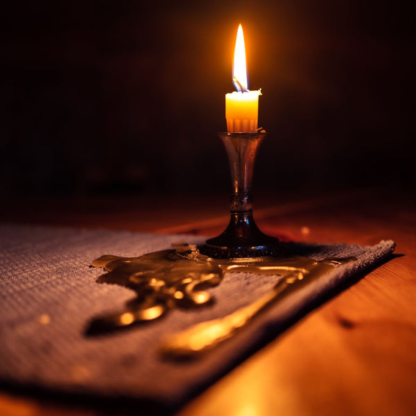 Close-up of a candle casting warm light in a dark setting, creating a cozy ambiance.