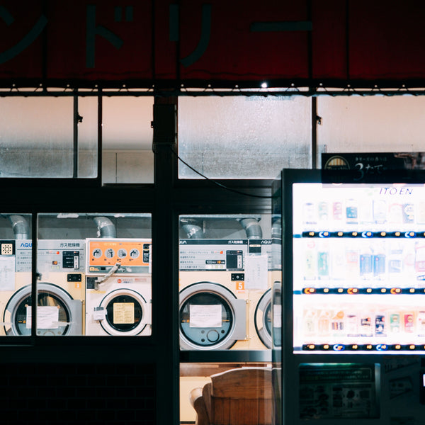 A cozy nighttime scene at a laundry shop with a bright vending machine and washing machines.