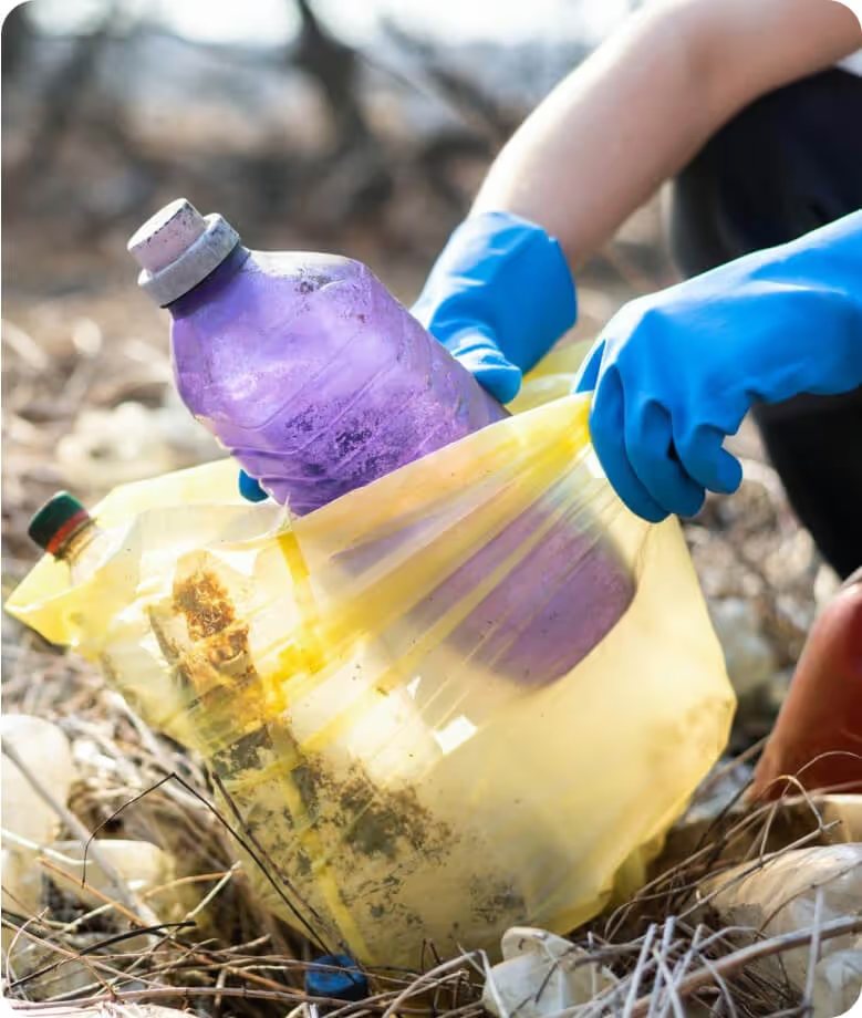 A person collecting plastic waste into a yellow bag
