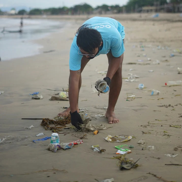 A volunteer picking up plastic litter on a beach